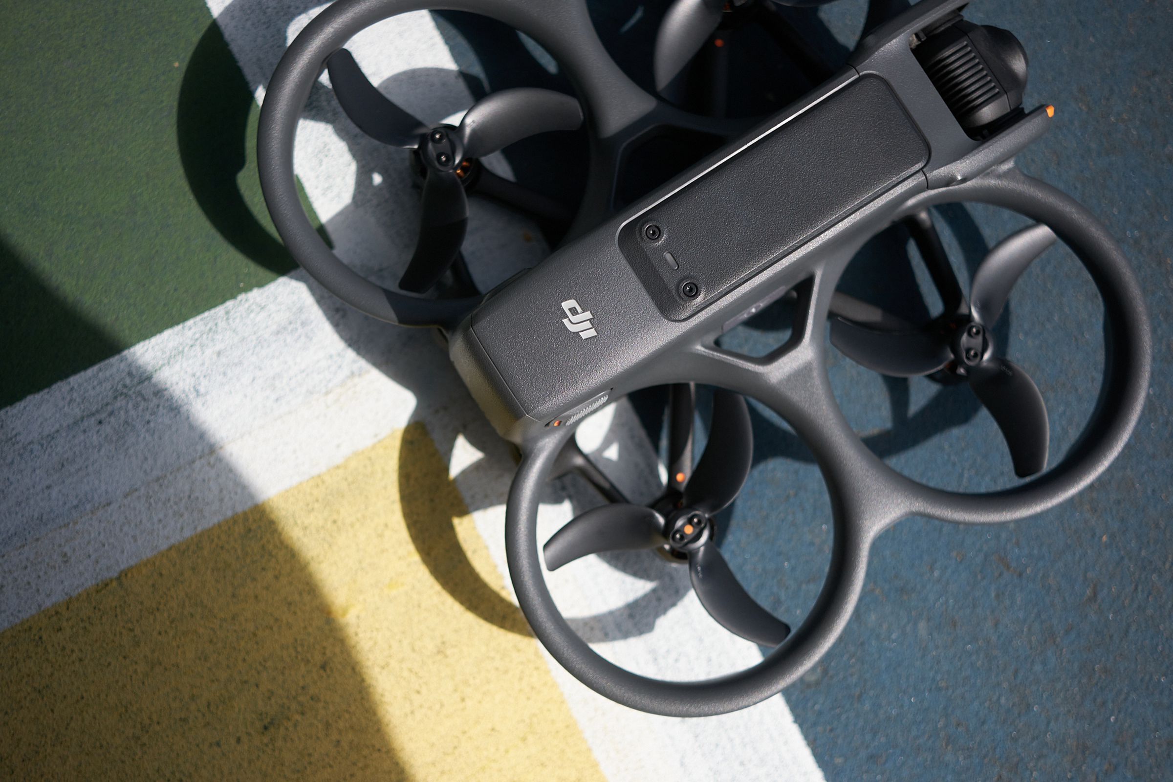 Tiga perempat gambar berisi kerangka dan baling-baling tiga bilah dari sebuah drone quadcopter dengan bodi abu-abu ramping dan kamera di salah satu ujungnya.